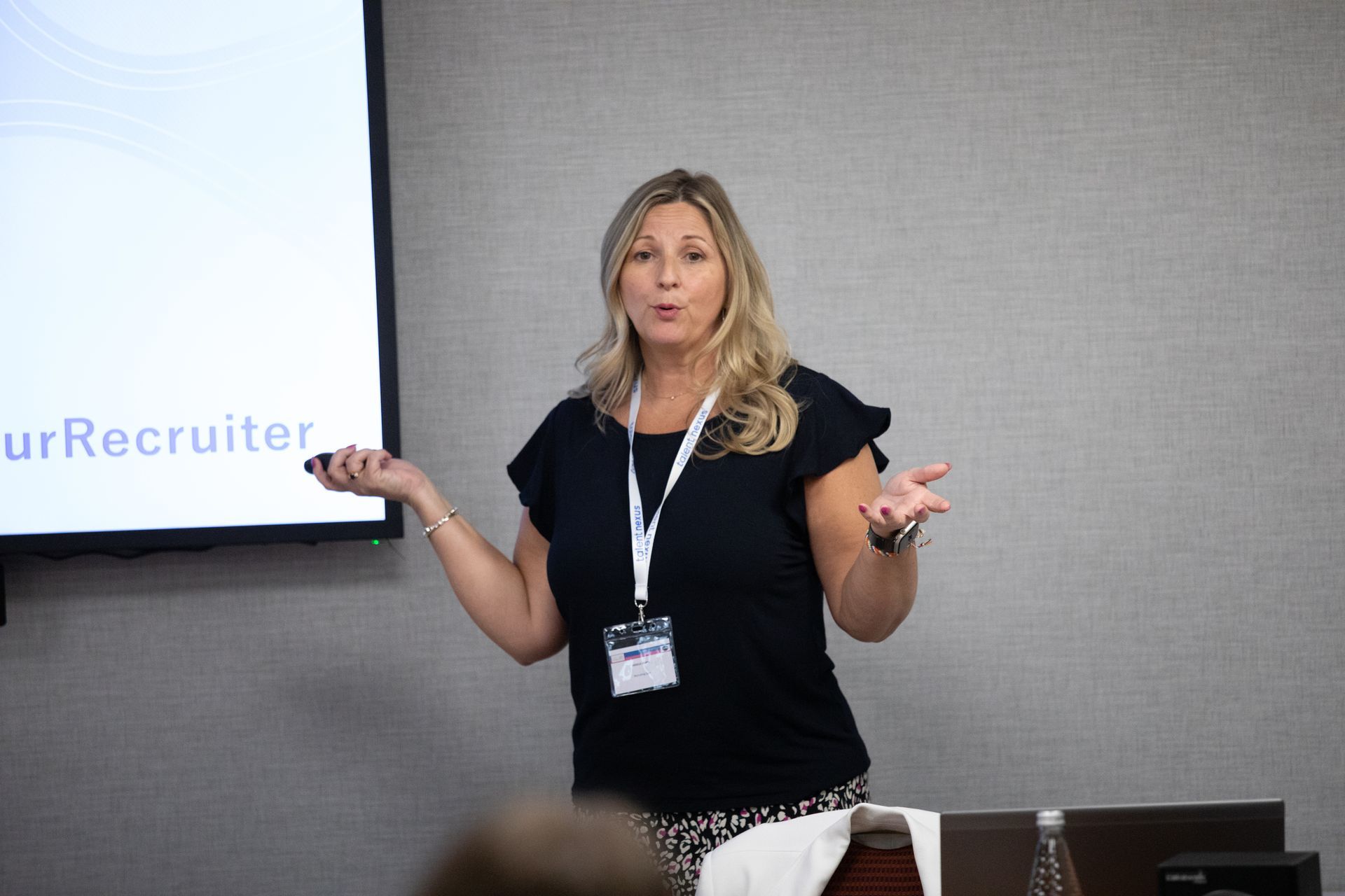 A woman is giving a presentation in front of a screen that says recruiter
