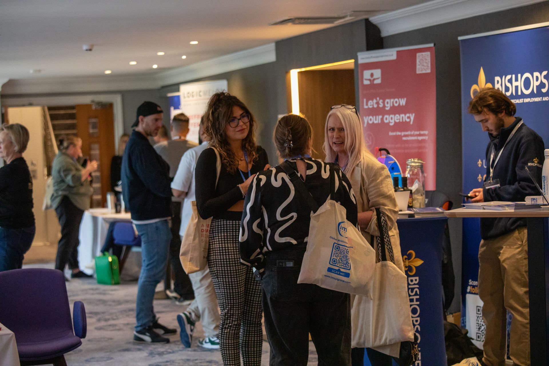A group of people are standing in a room talking to each other.