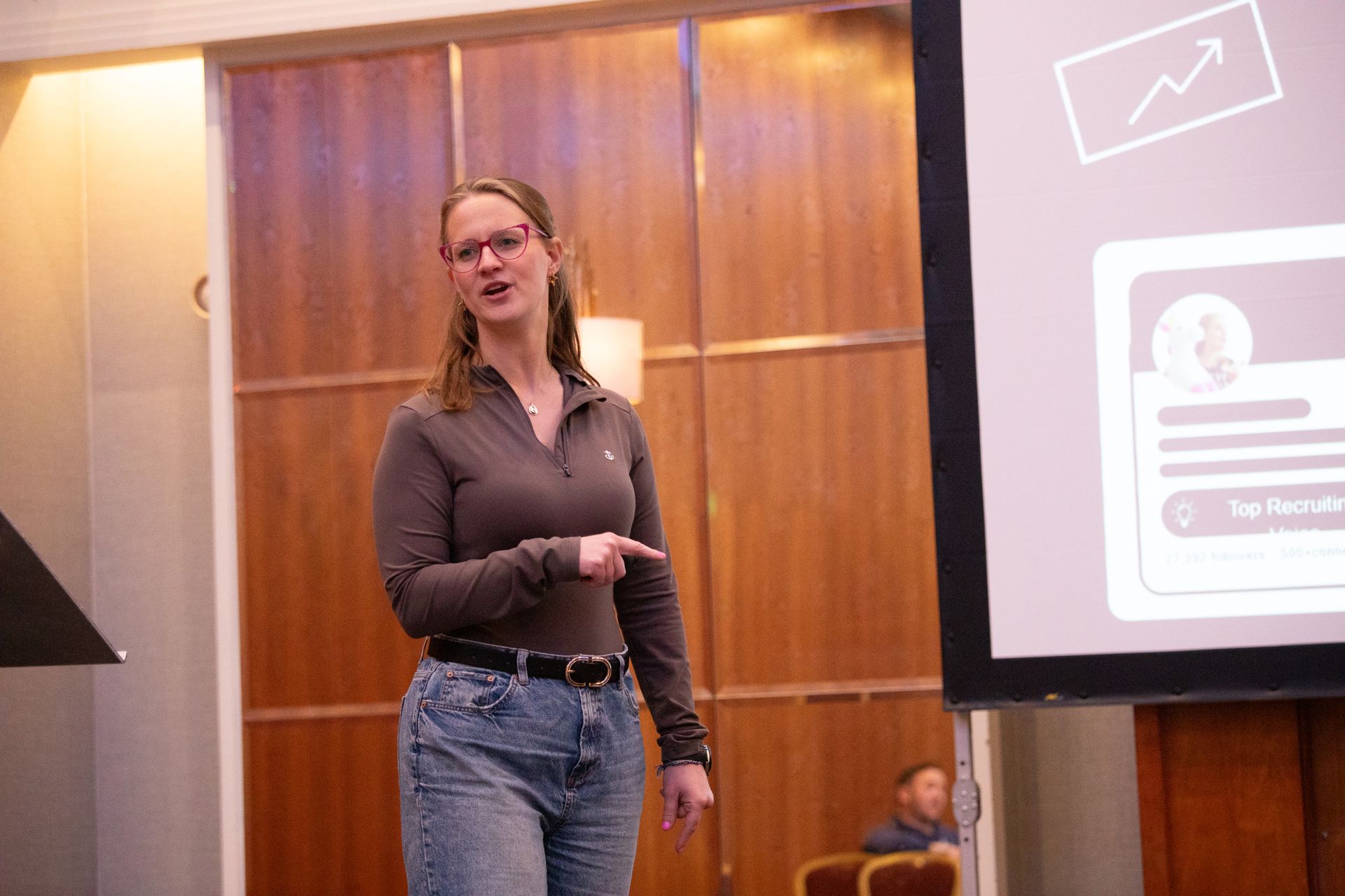 A woman is giving a presentation in front of a large screen.