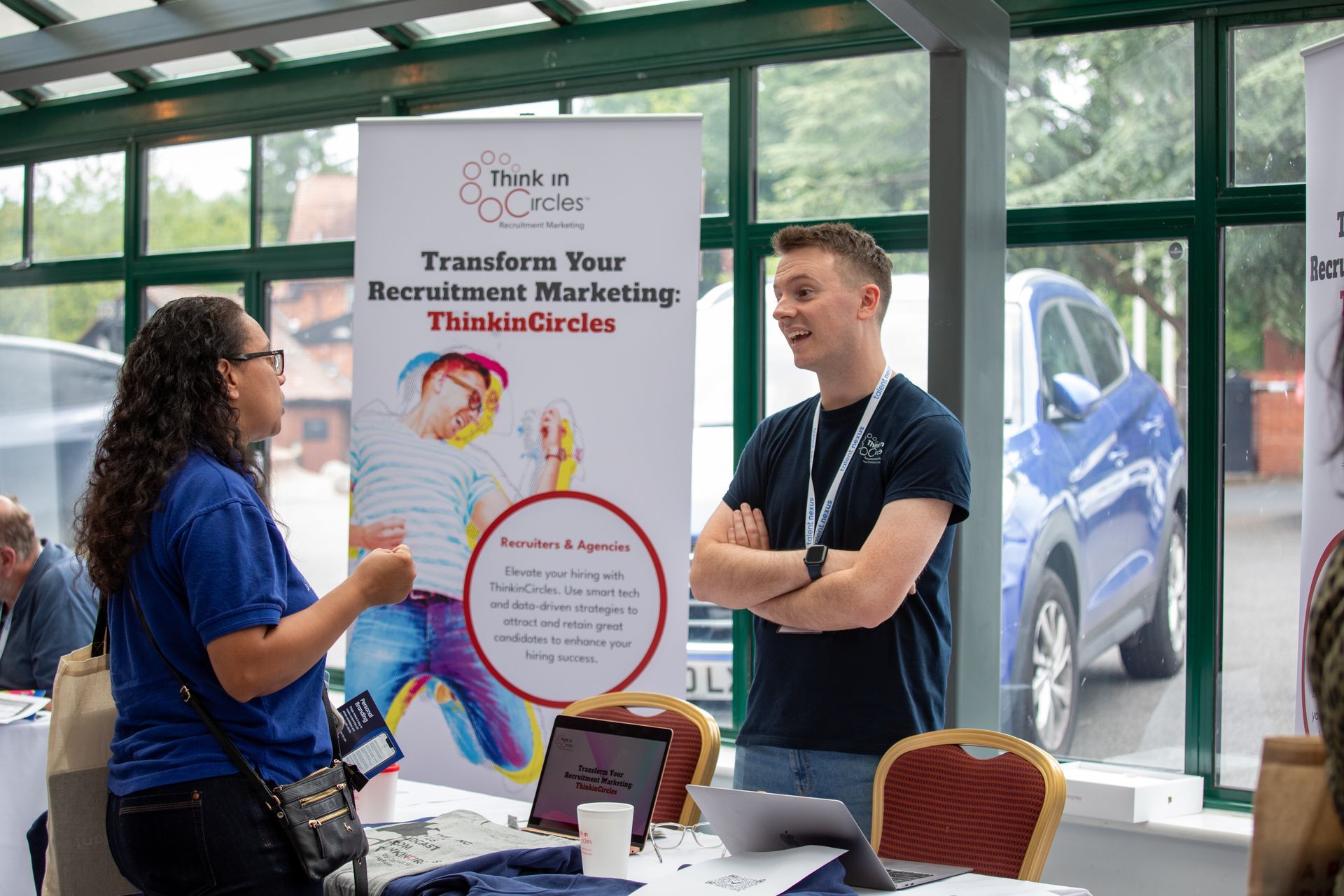 A man and a woman are talking at a table at a job fair.