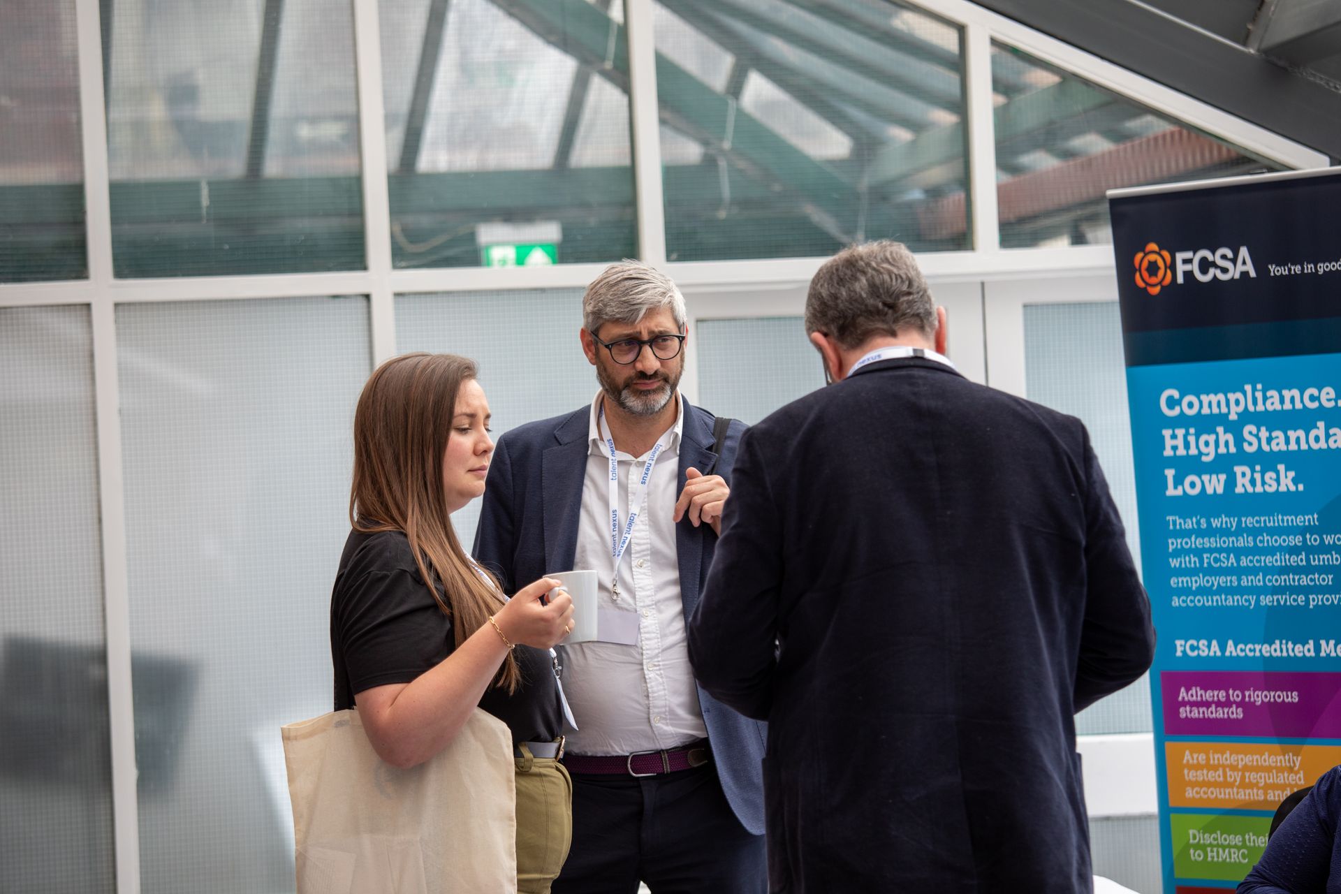 A group of people are standing in front of a sign that says compliance high standards low risk.