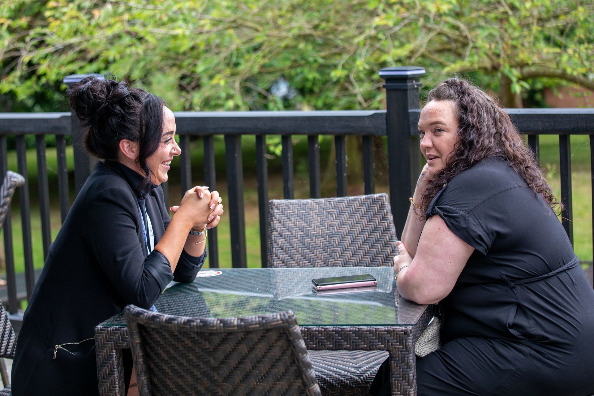 Two women are sitting at a table talking to each other.