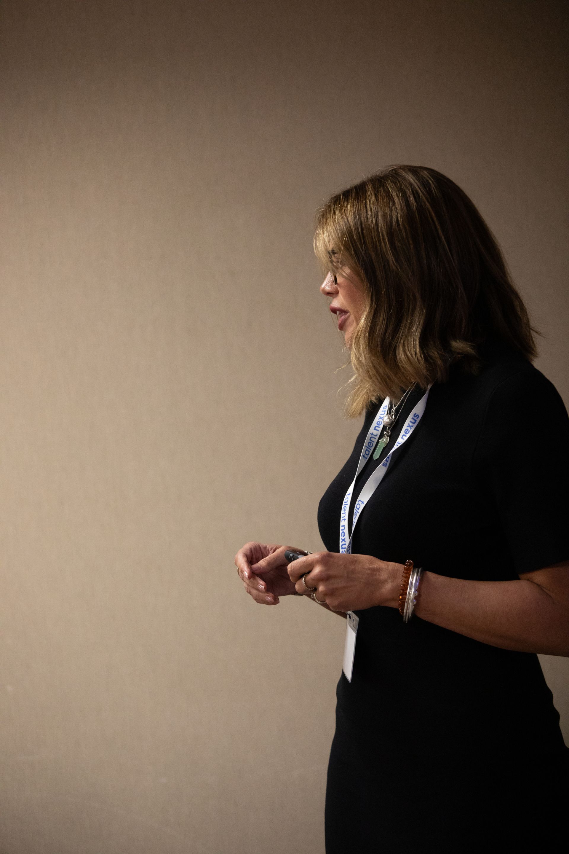 A woman in a black dress is standing in front of a wall.