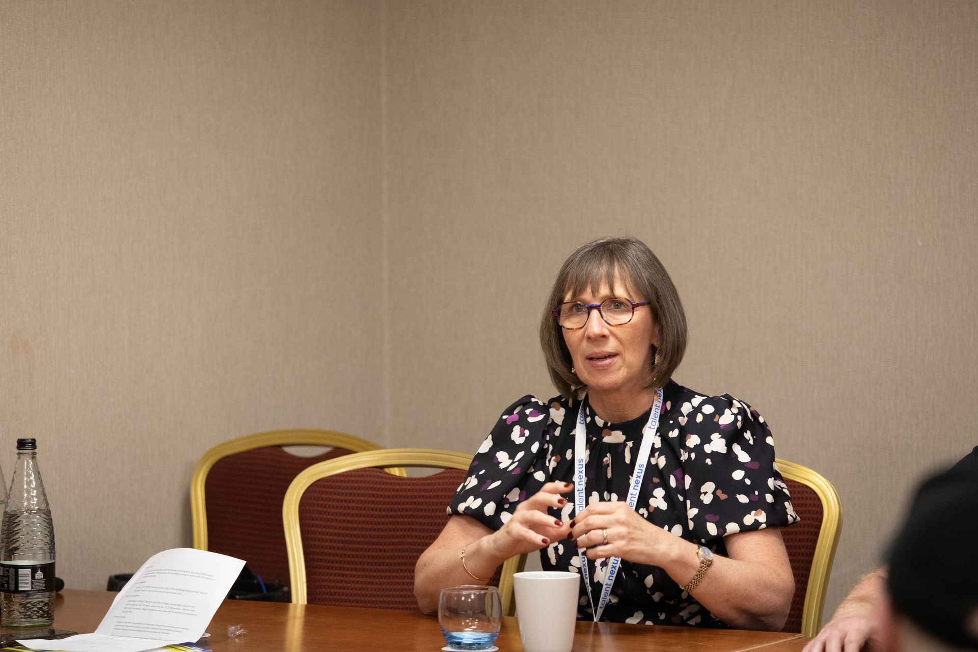 A woman is sitting at a table talking to a group of people.