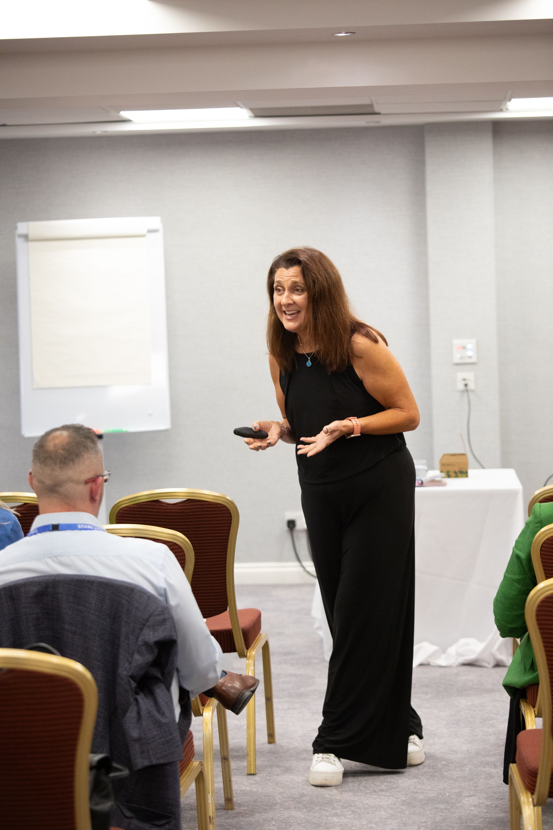 A woman is standing in front of a group of people in a conference room.