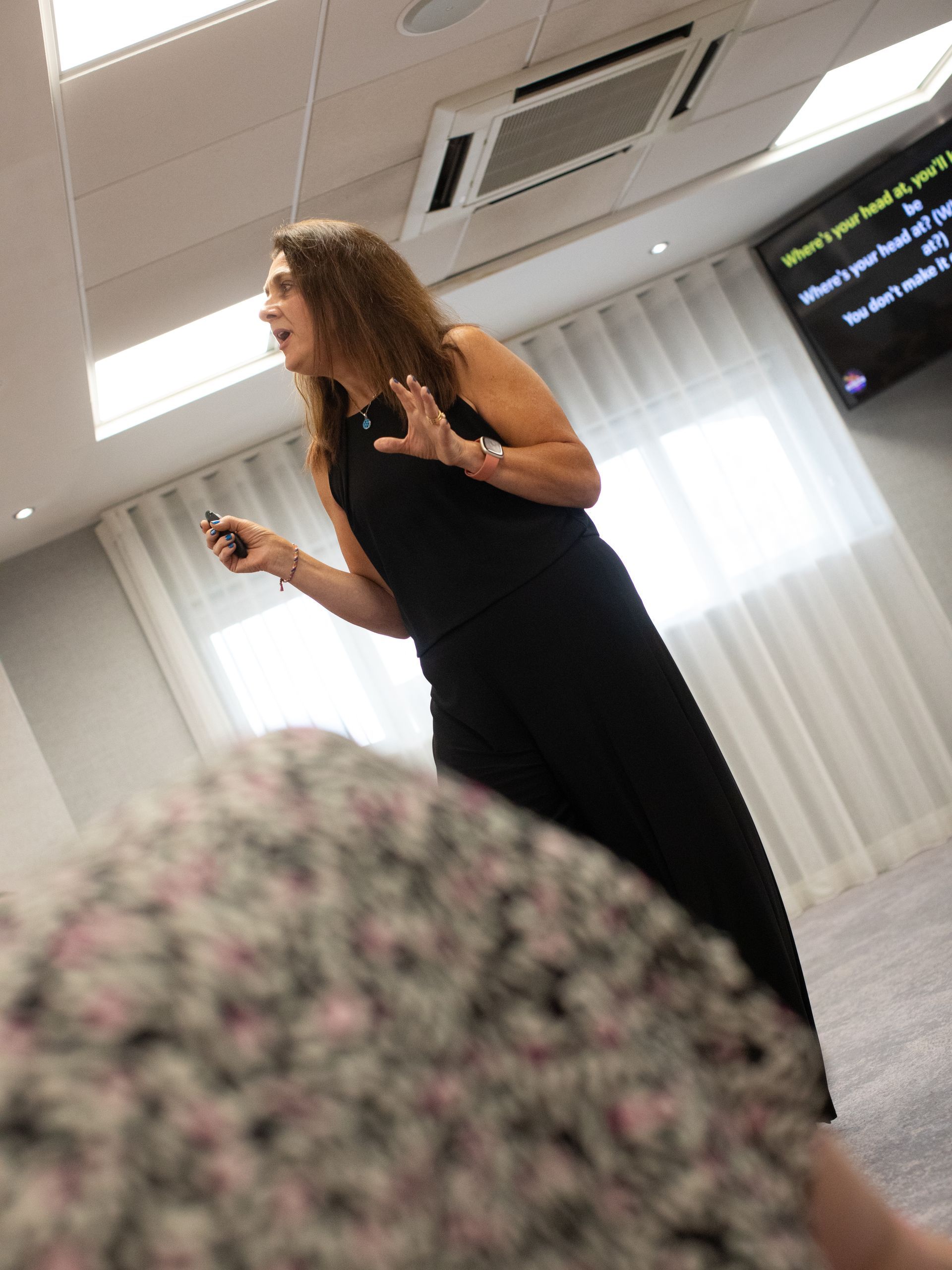 A woman in a black dress is giving a presentation in a room.
