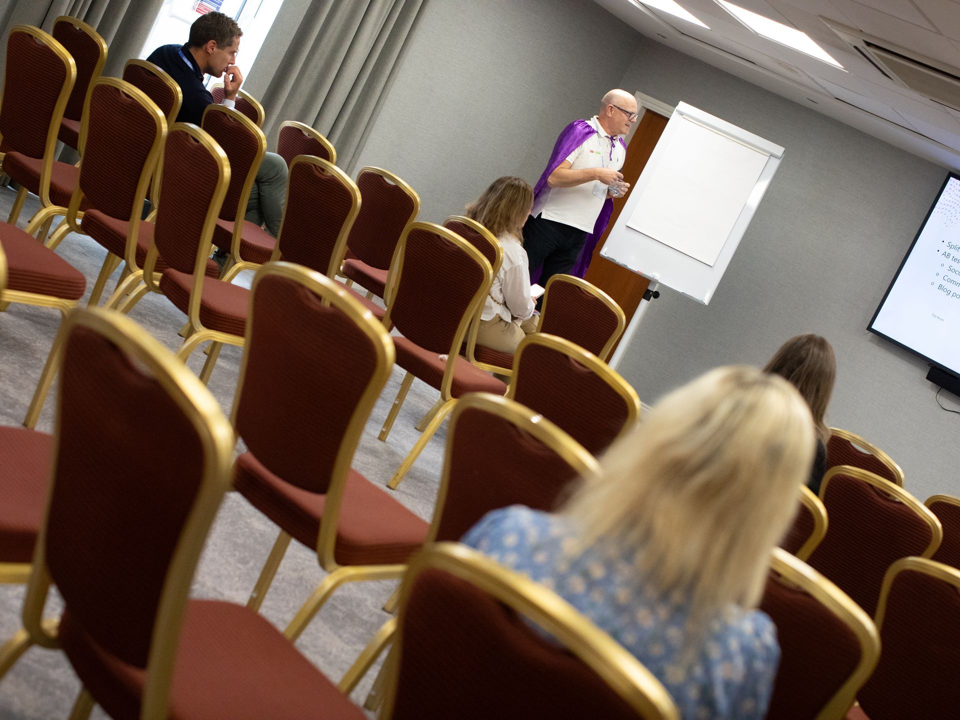 A group of people are sitting in rows of chairs in a conference room
