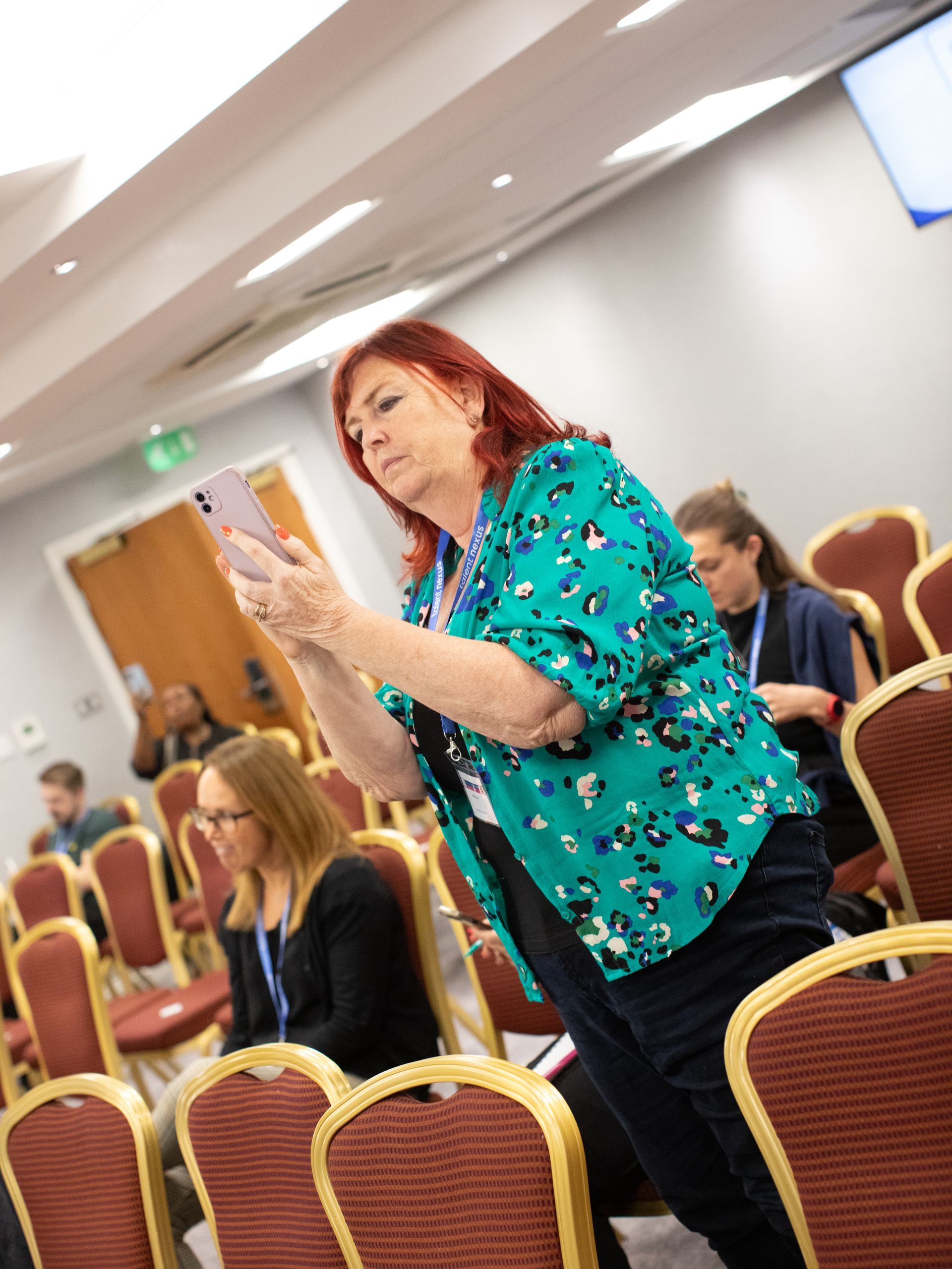 A woman is standing in a conference room looking at her phone.