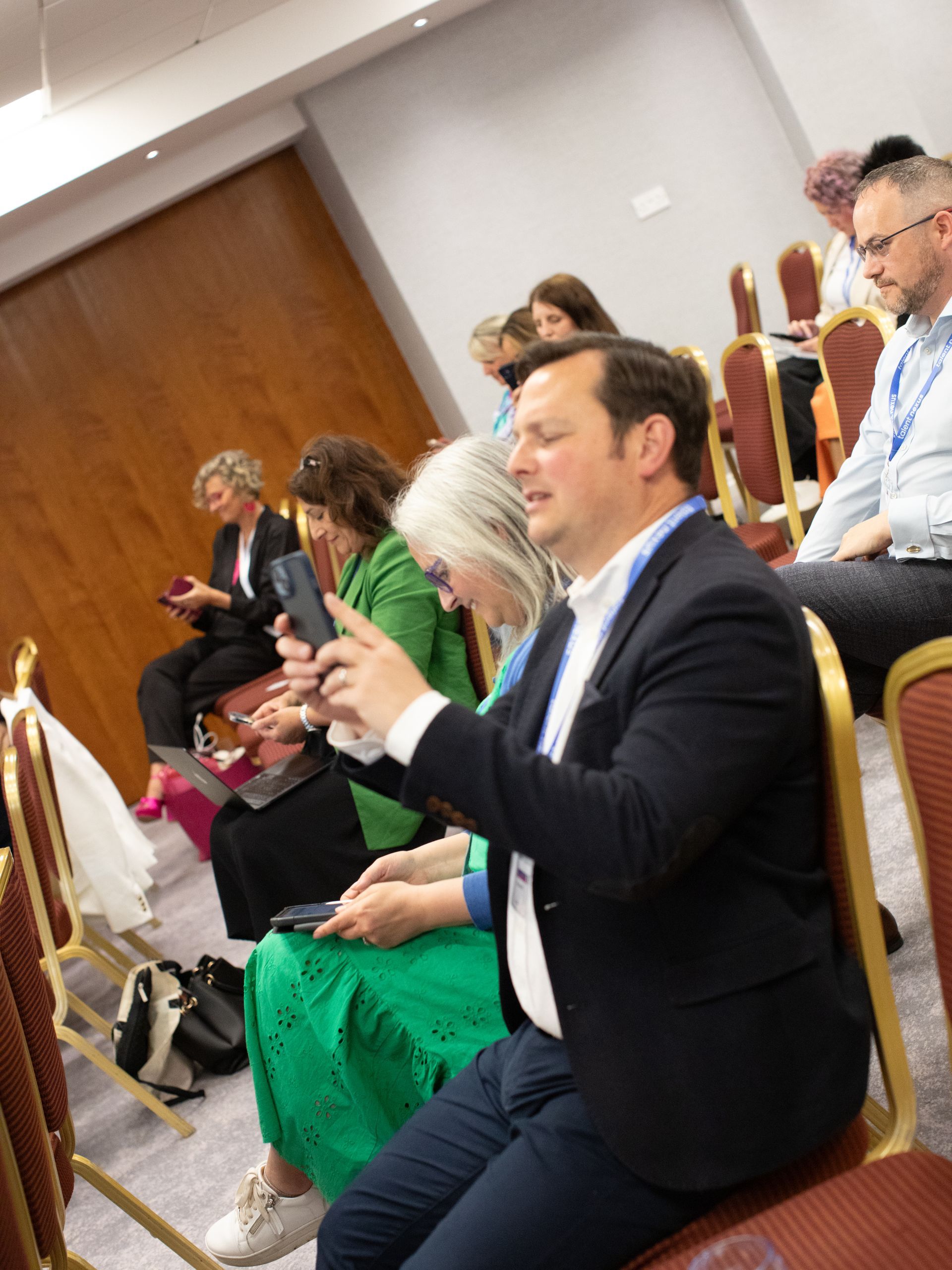 A group of people are sitting in chairs looking at their phones.