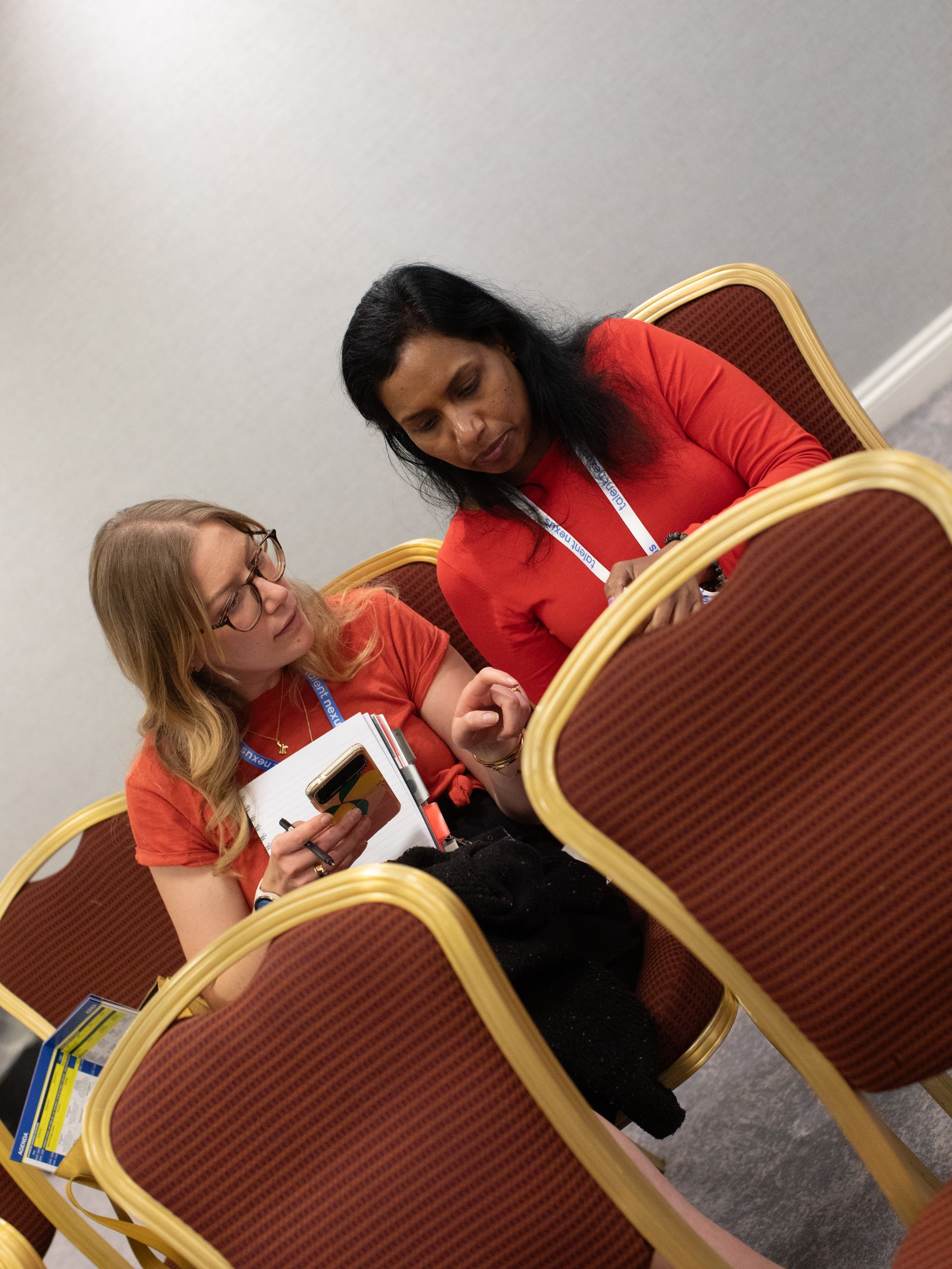 Two women are sitting in chairs looking at a book