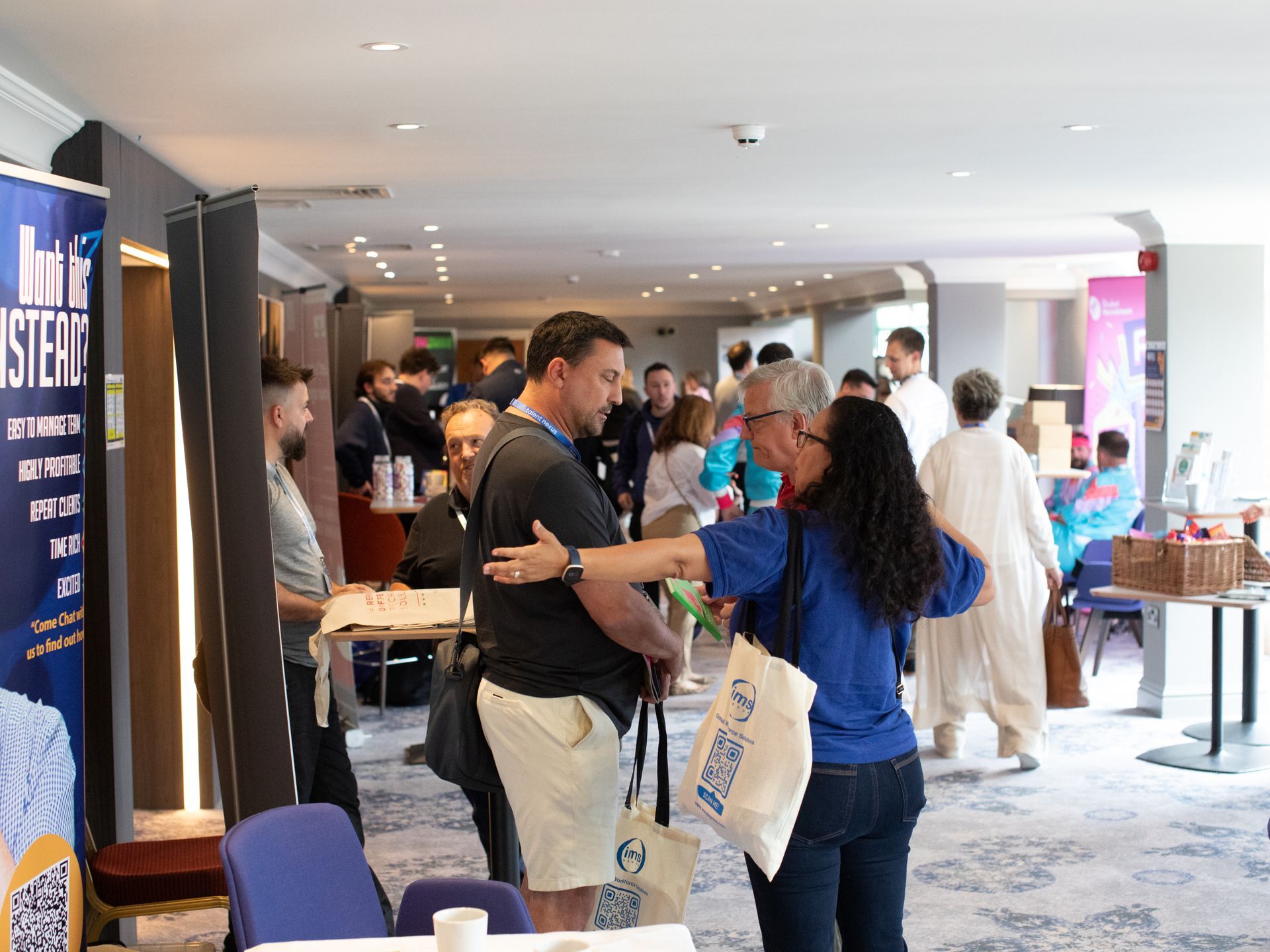 A group of people are standing in a room talking to each other.