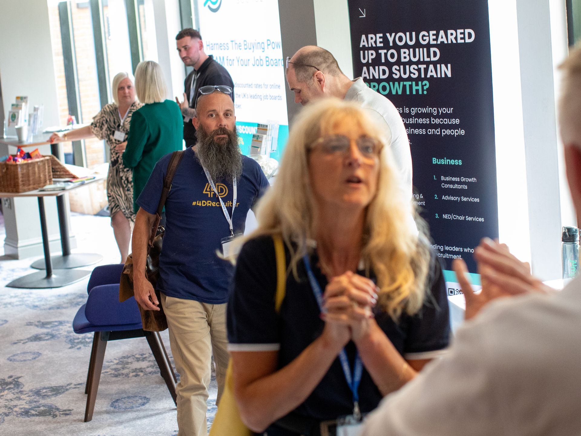 A group of people are standing in front of a sign that says `` are you geared up to build and sustain growth ? ''