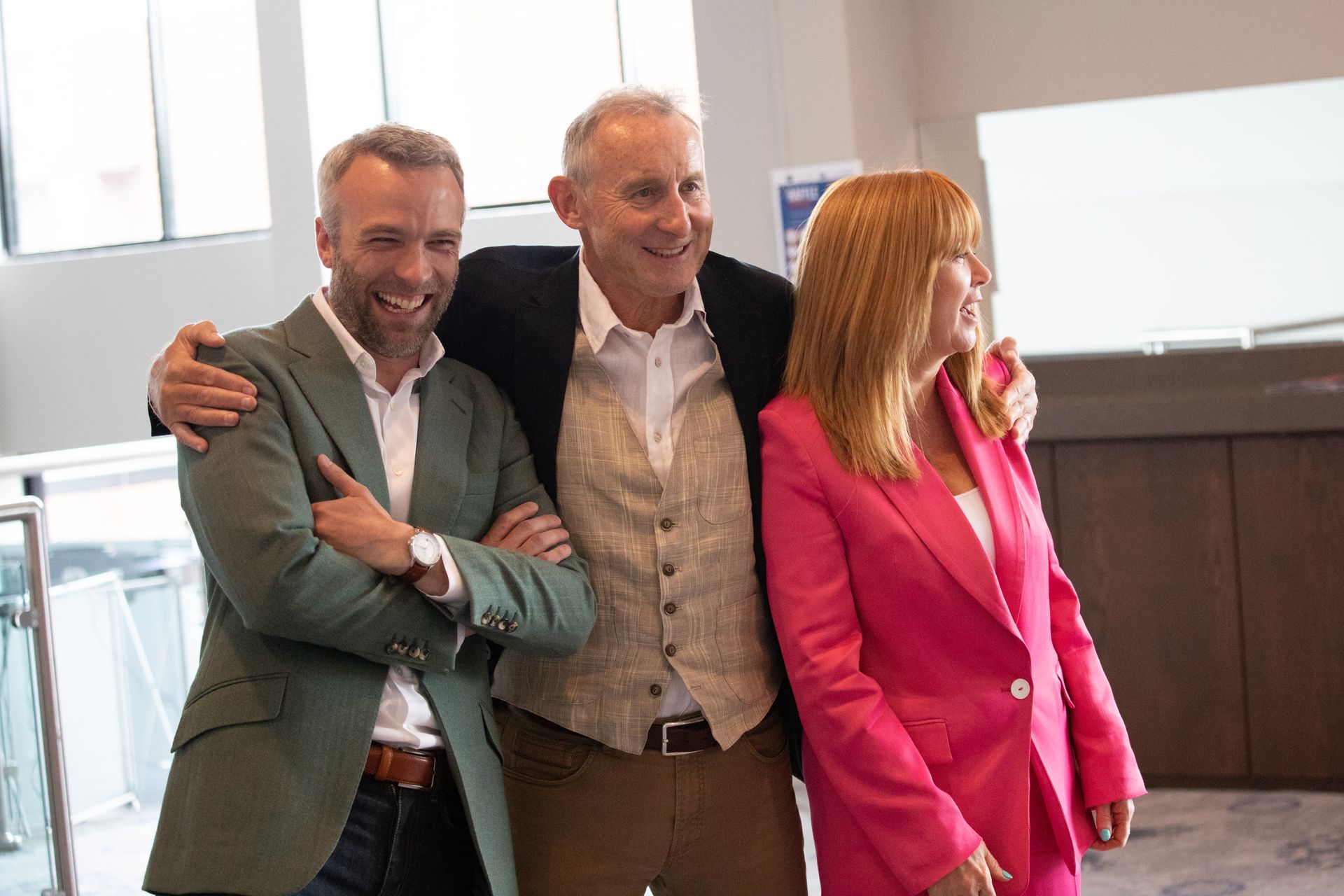 A man in a green jacket and a woman in a pink jacket are posing for a picture.