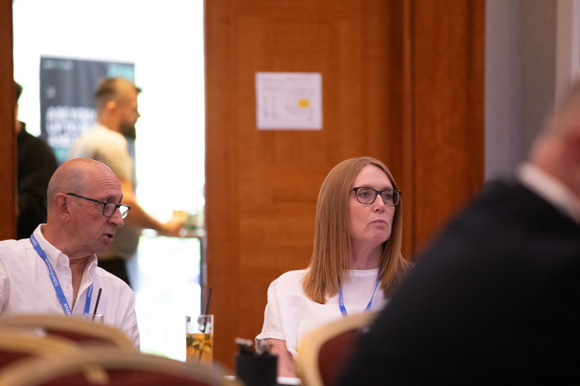 A man and a woman are sitting at a table in a room.