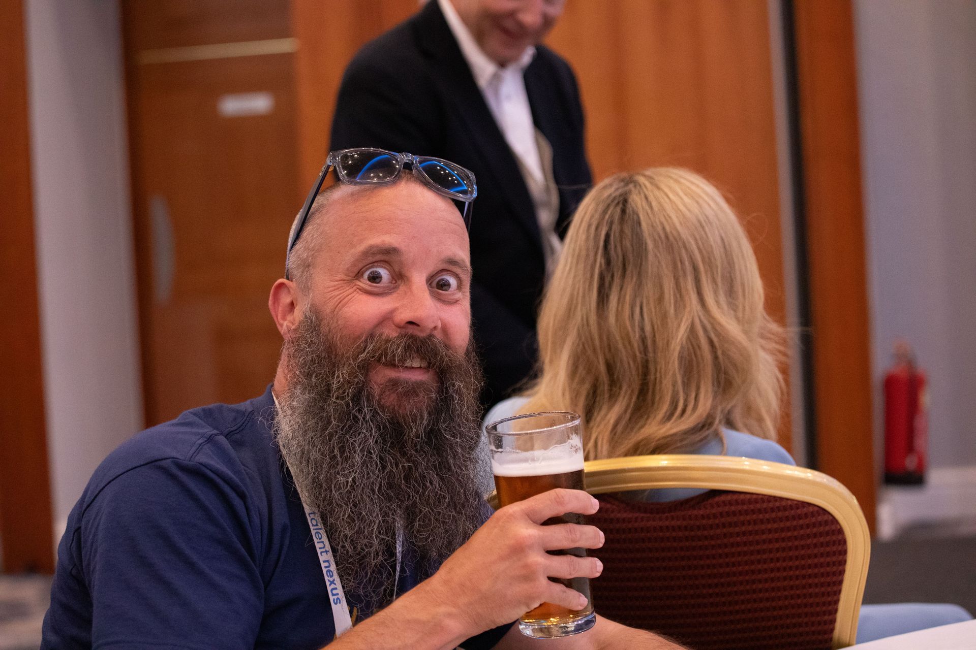 A man with a beard is holding a glass of beer.