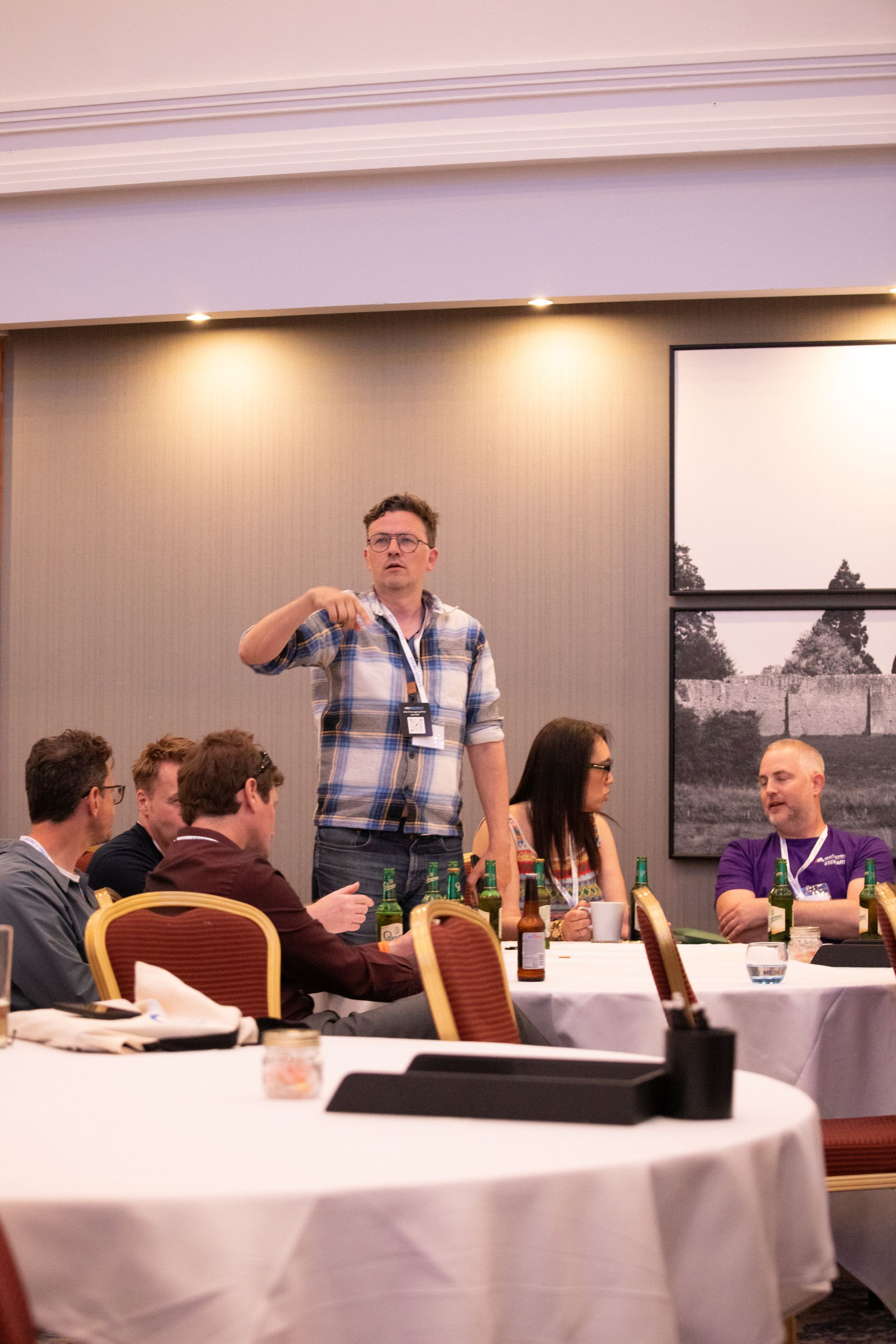 A man is standing in front of a group of people sitting at tables.