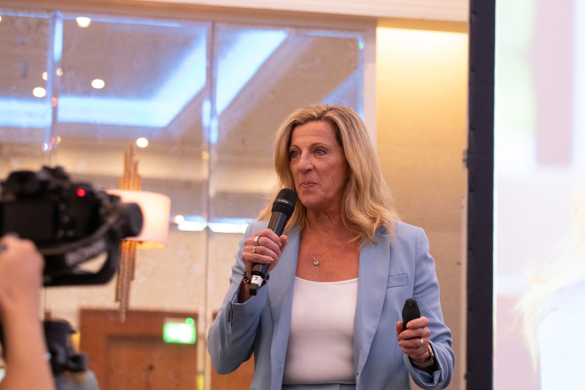 A woman is holding a microphone in front of a camera.