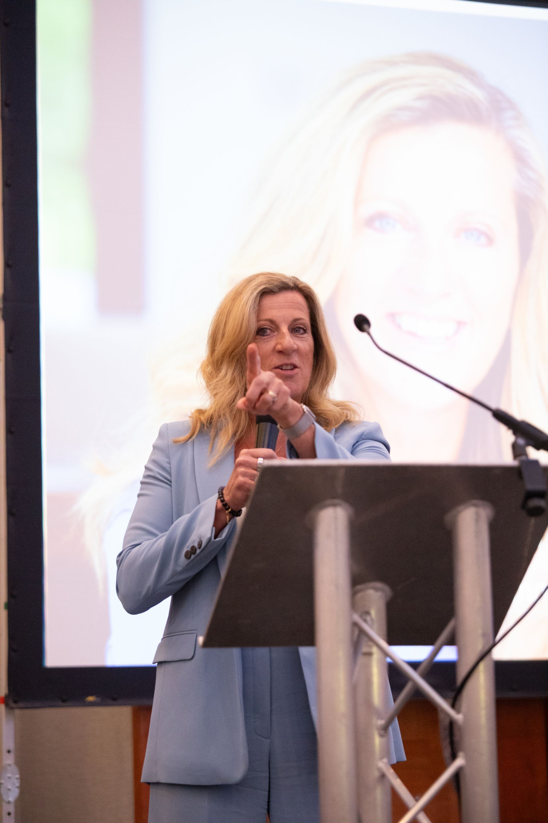 A woman is standing at a podium holding a microphone.