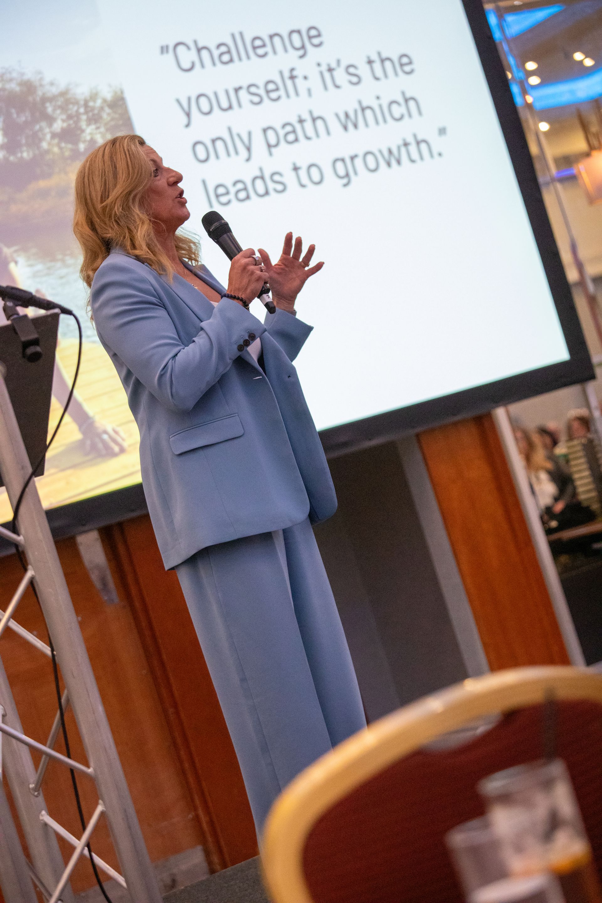 A woman in a blue suit is giving a presentation