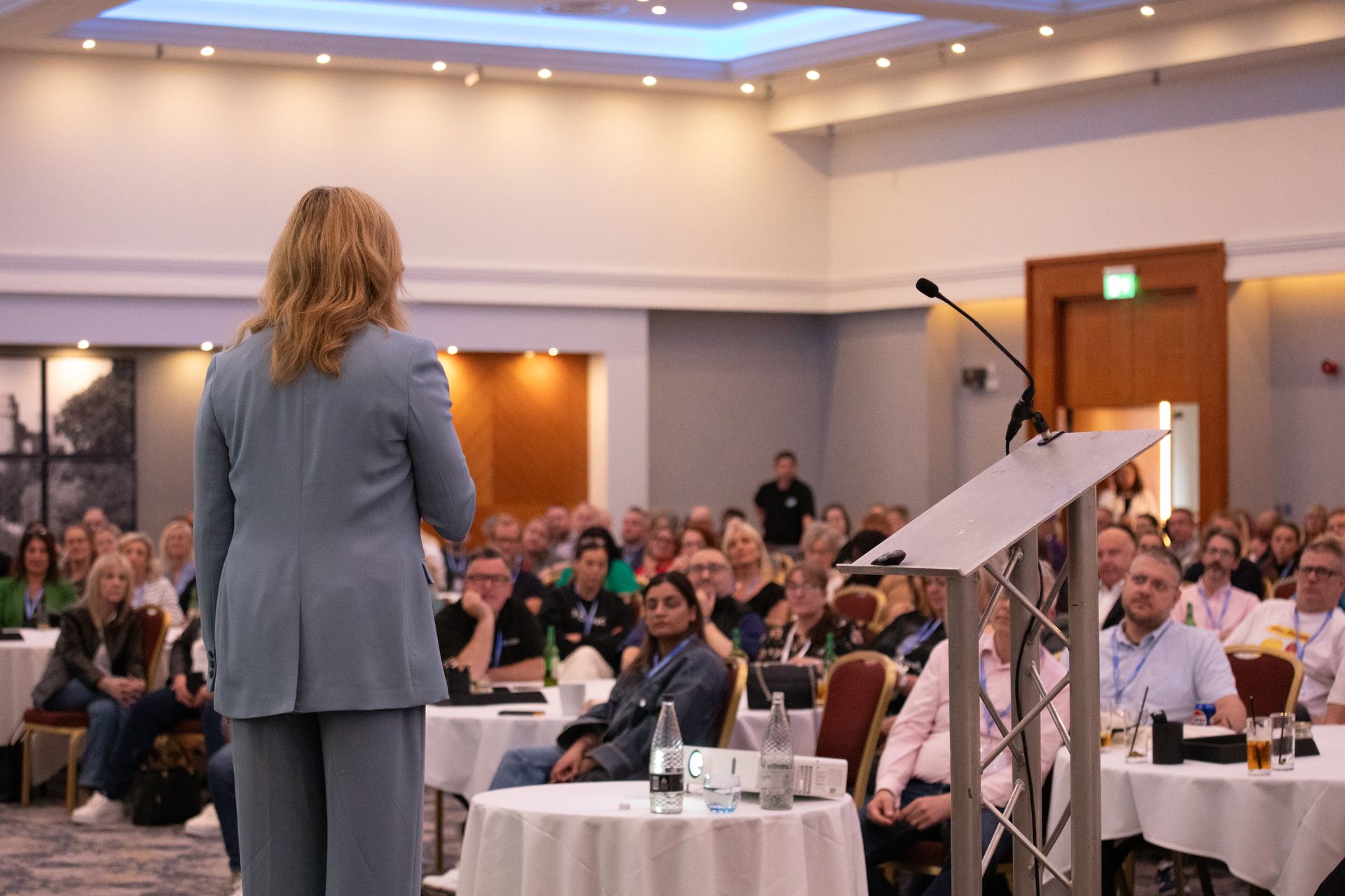 A woman is standing at a podium in front of a crowd of people.