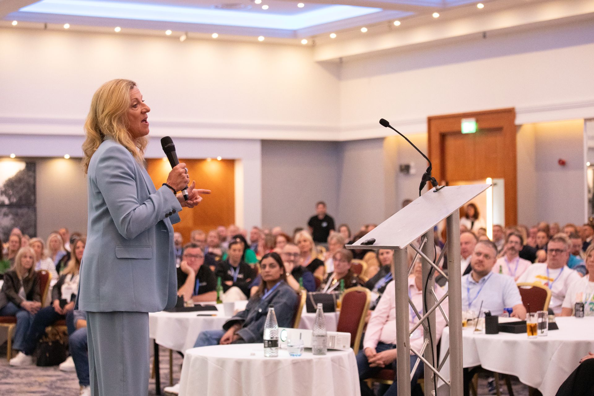 A woman is standing at a podium giving a presentation to a large group of people.