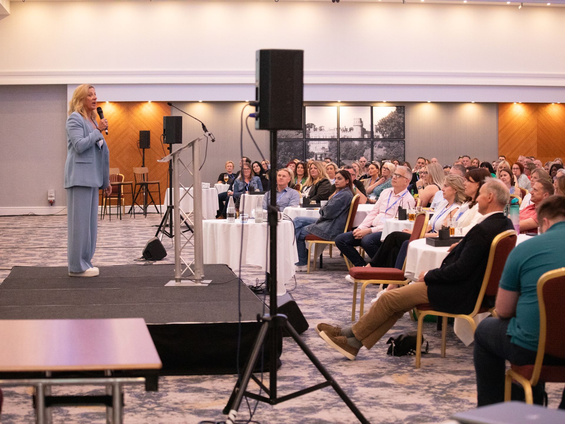 A woman is standing on a stage giving a presentation to a large group of people.