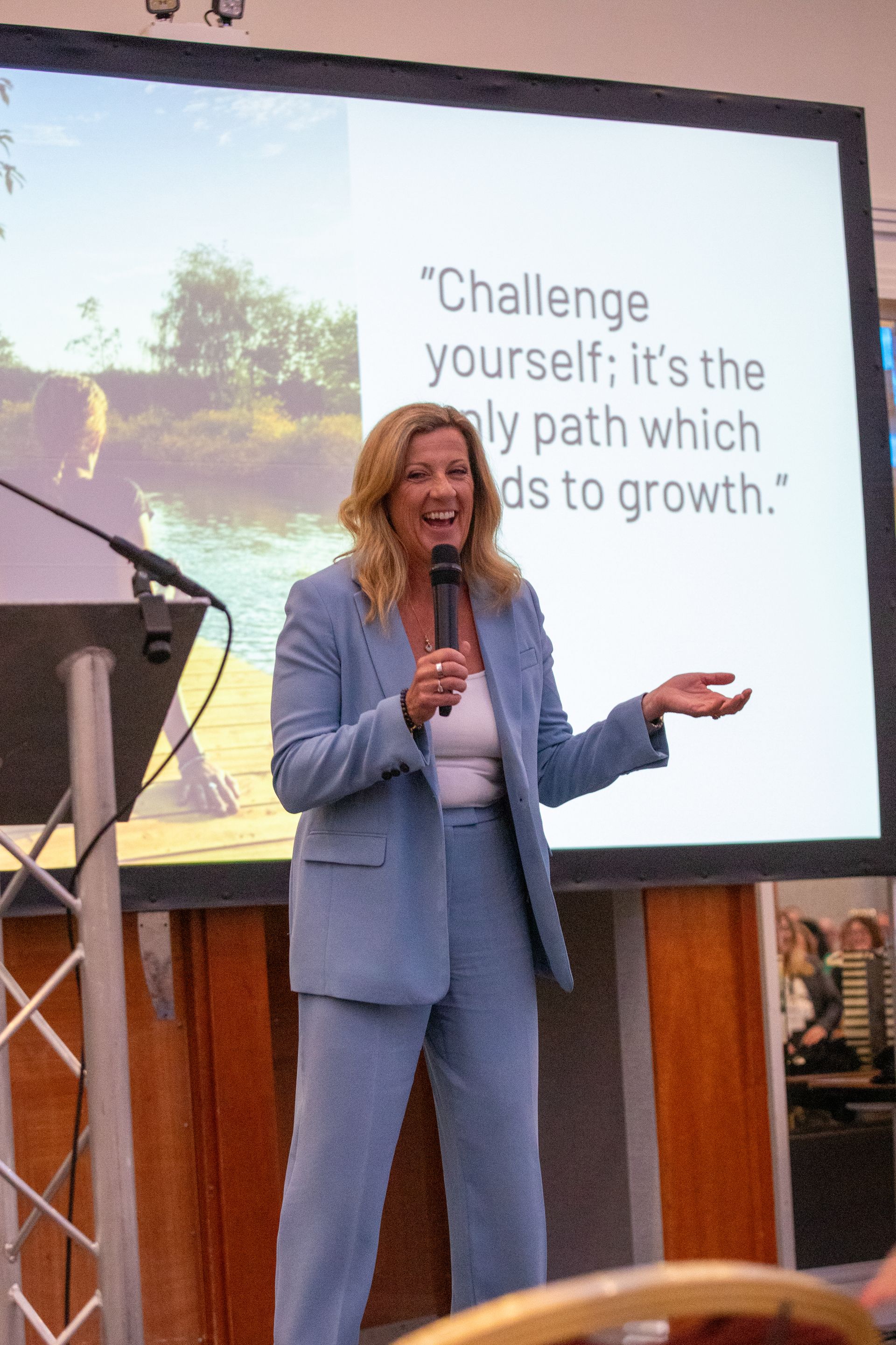 A woman in a blue suit is giving a presentation