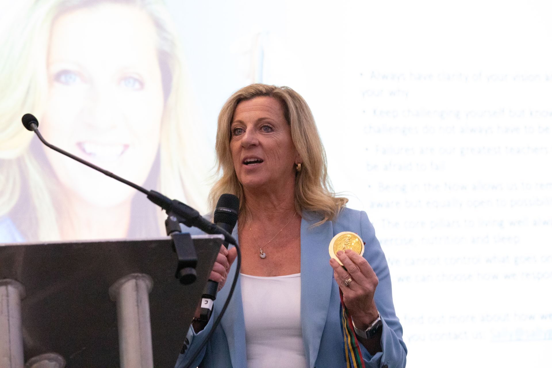 A woman is holding an orange and speaking into a microphone.