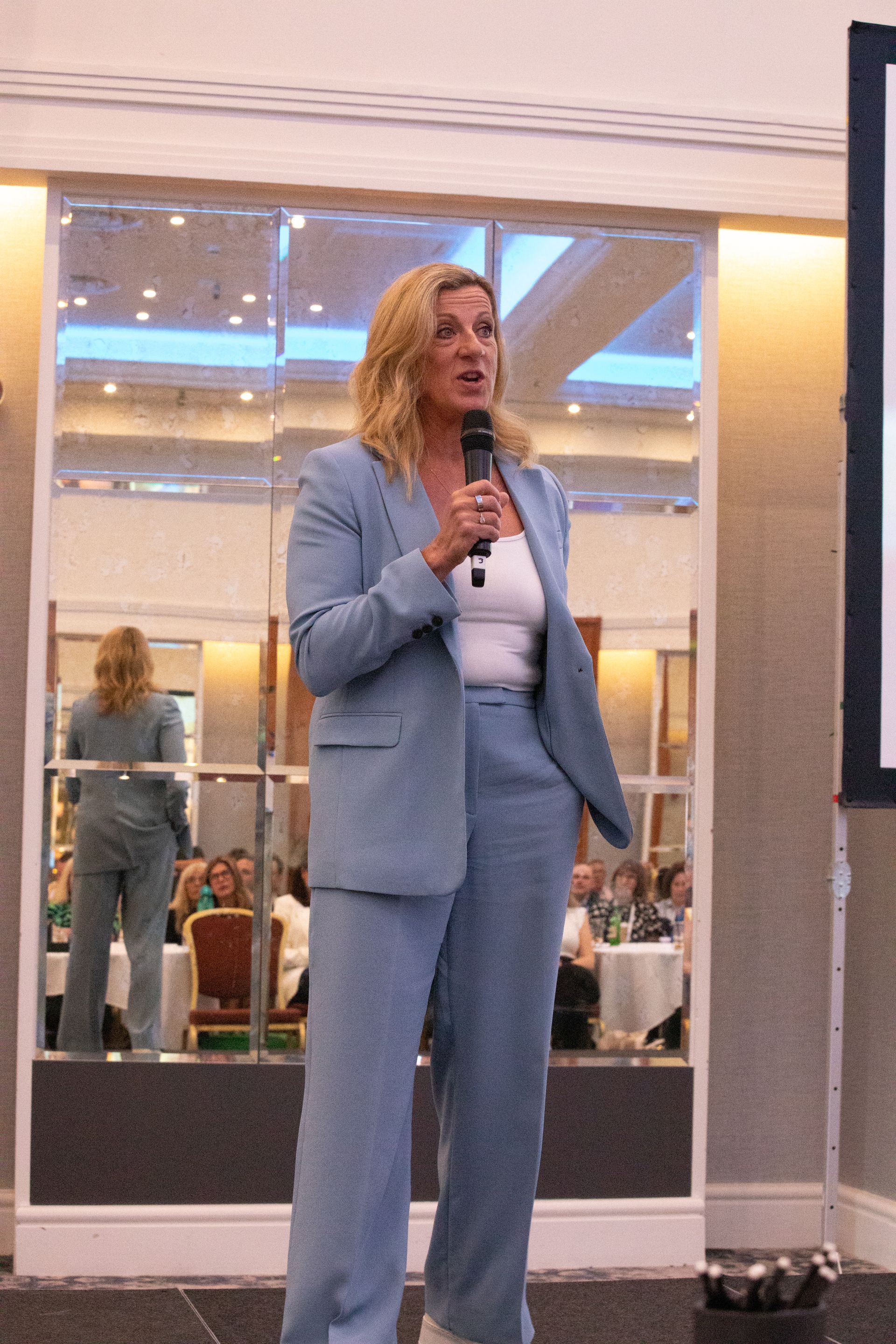 A woman in a suit is speaking into a microphone