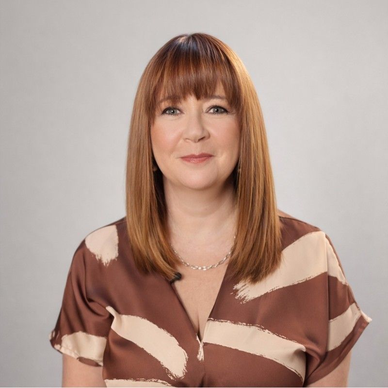 A man in a grey shirt is smiling for the camera