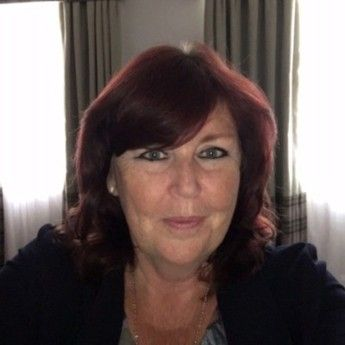 A woman with long dark hair is smiling for the camera.