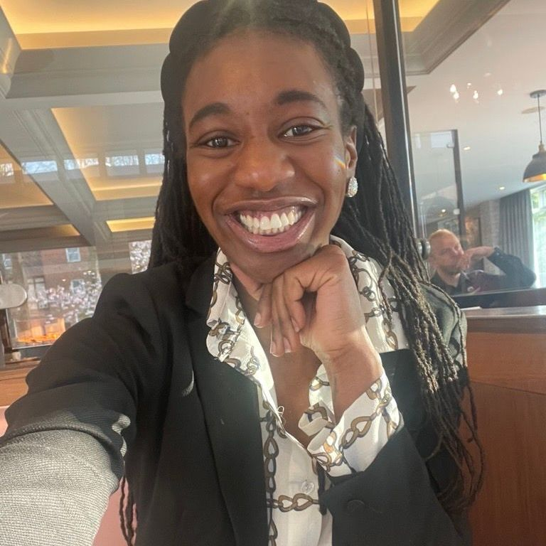 A woman wearing glasses and a necklace is smiling for the camera.