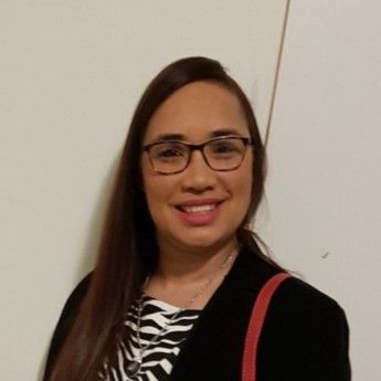 A woman with long dark hair is smiling for the camera.