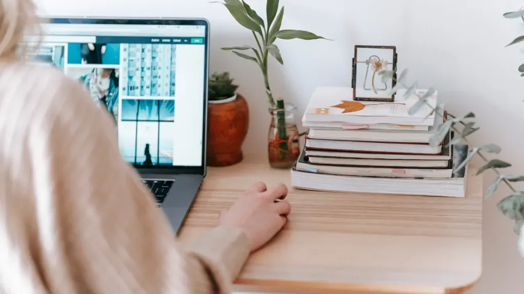 A woman is sitting at a desk using a laptop computer.