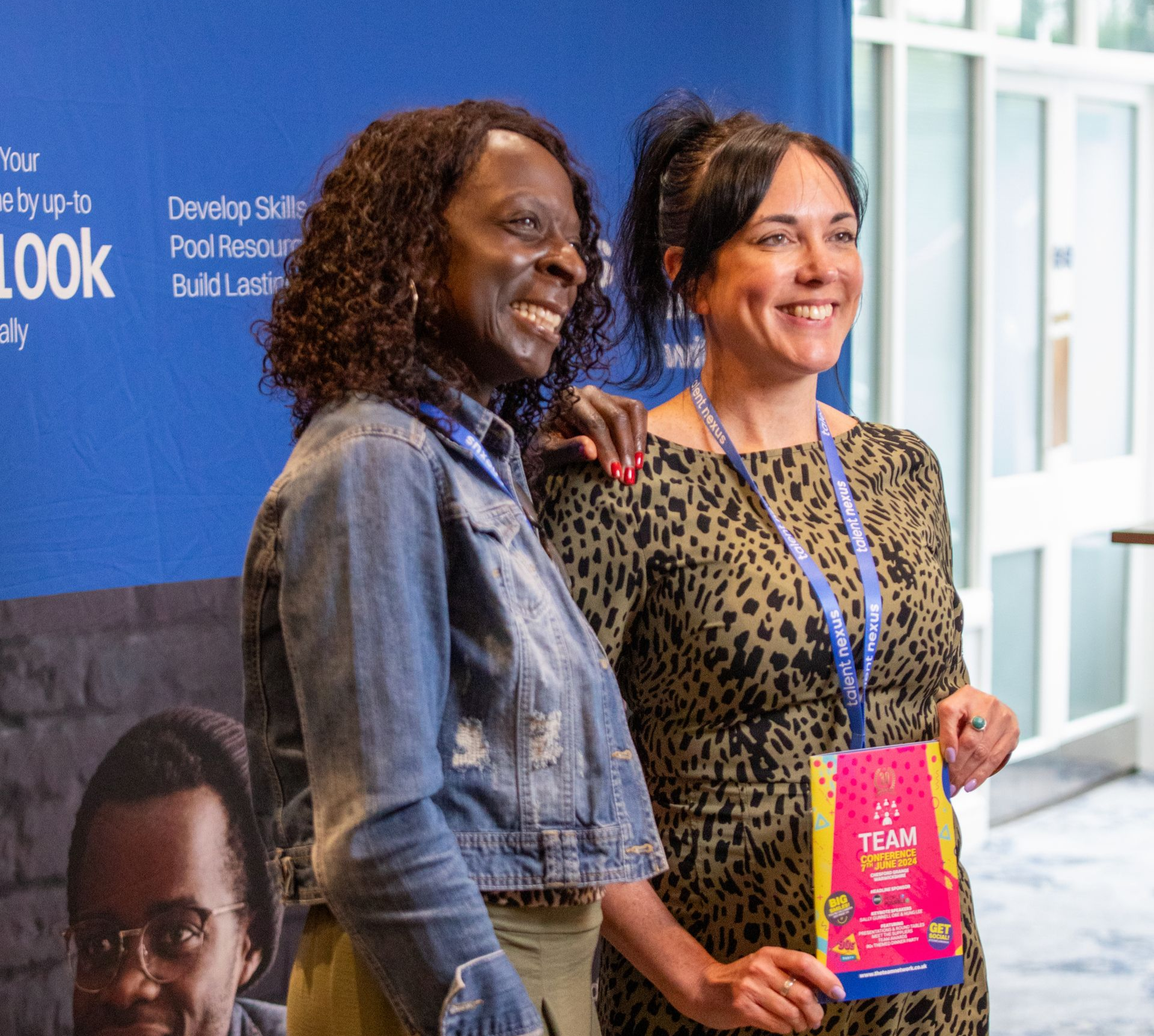 Two women are posing for a picture in front of a sign that says team