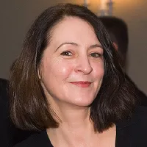 A woman with long dark hair is smiling for the camera.