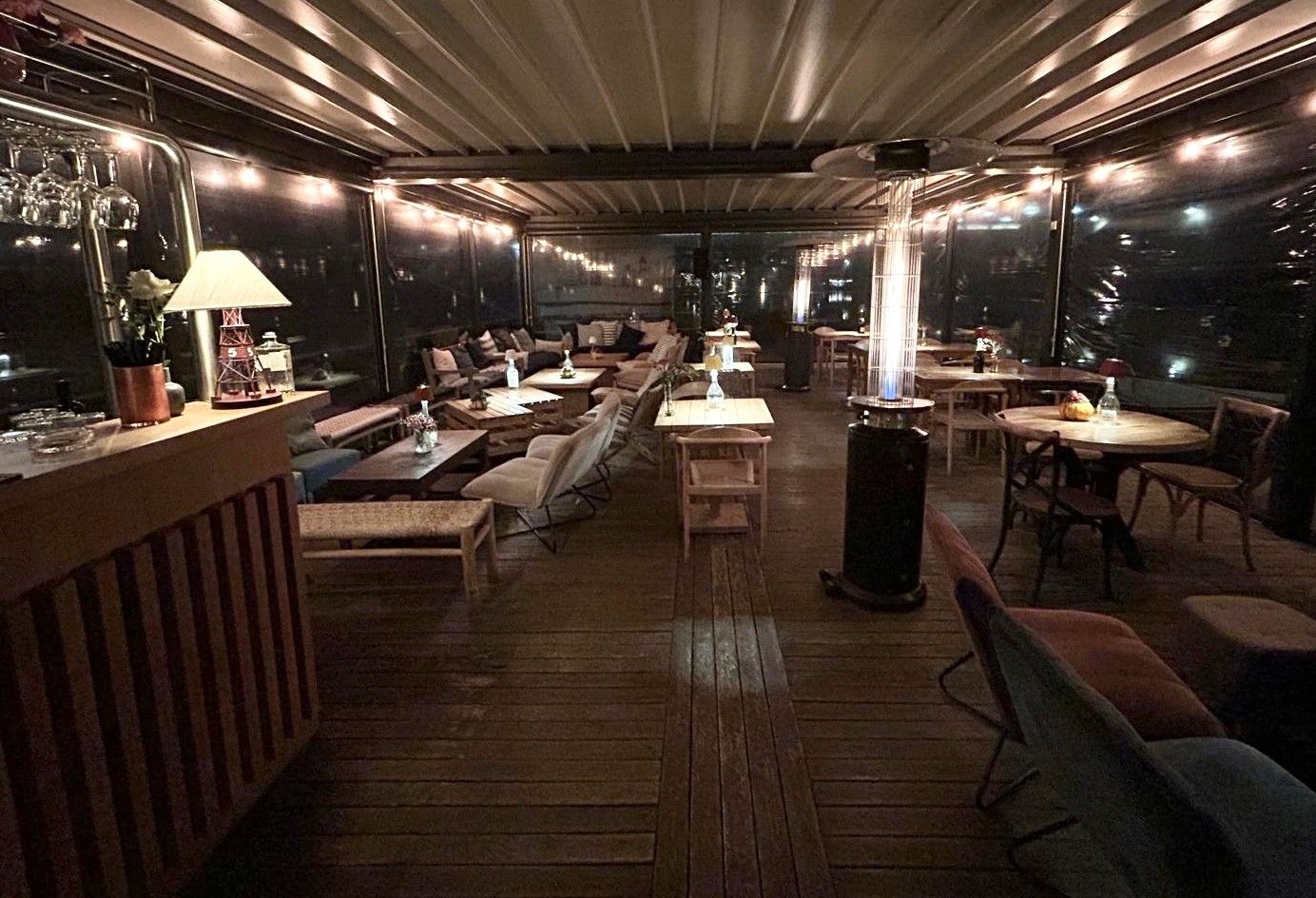 Un gruppo di persone è seduto a dei tavoli sotto gli ombrelloni di un ponte.