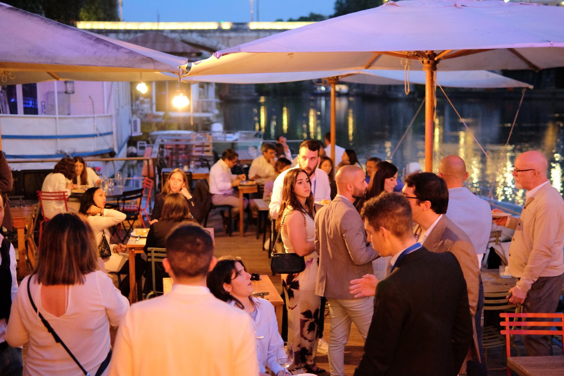 Un gruppo di persone è in piedi sotto gli ombrelli in un ristorante.