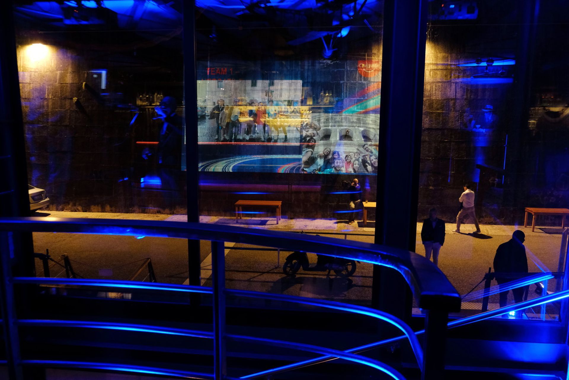 Un gruppo di persone è in piedi davanti a un grande schermo in una stanza buia.