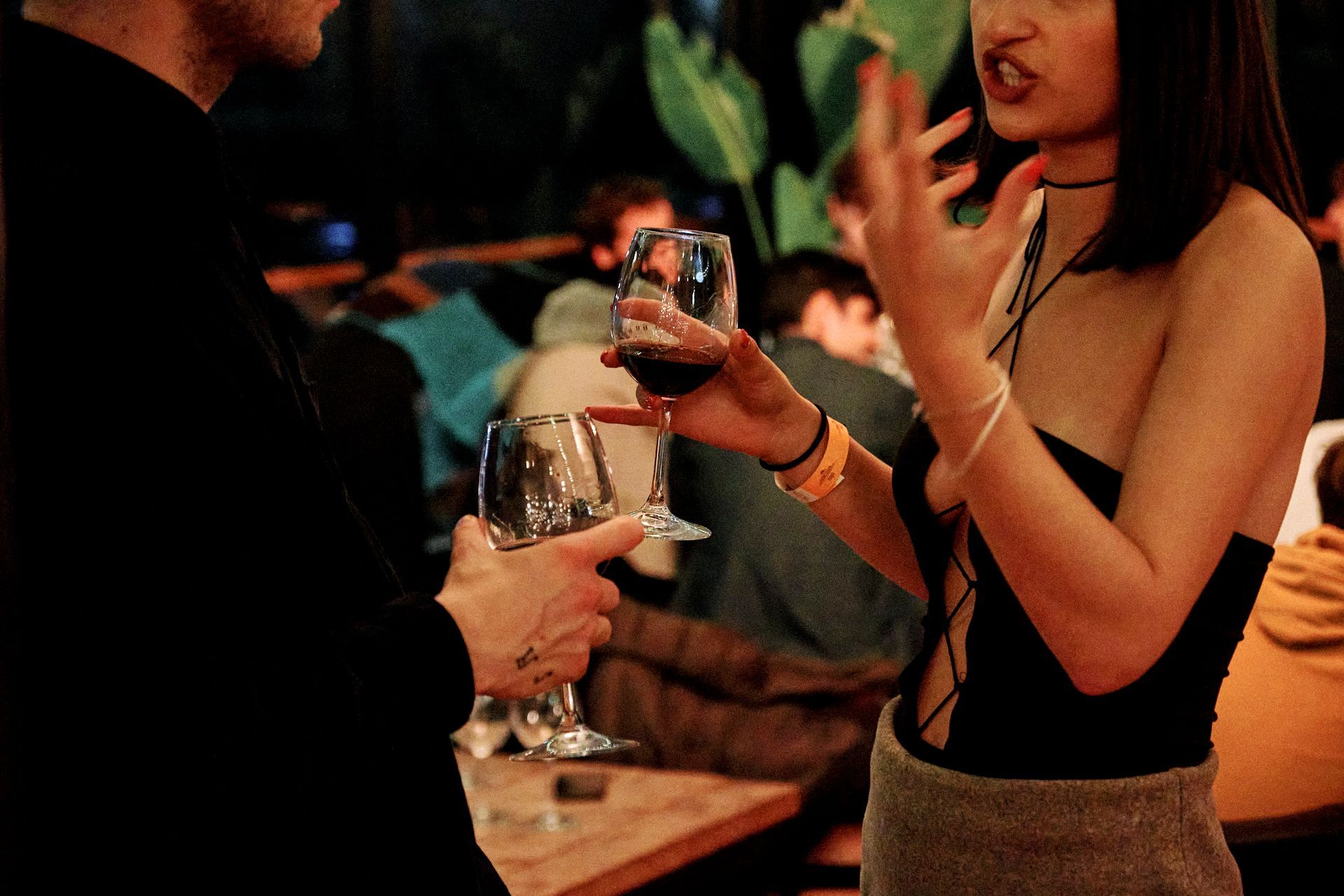 Un uomo e una donna sono in piedi uno accanto all'altra e tengono in mano dei bicchieri di vino.