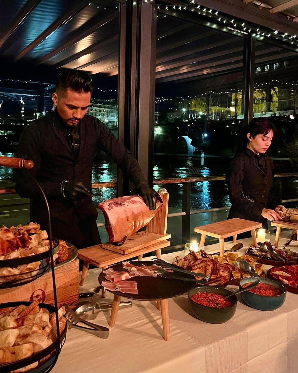 Un ristorante con tavoli e sedie che si affaccia su un fiume con un ponte sullo sfondo.
