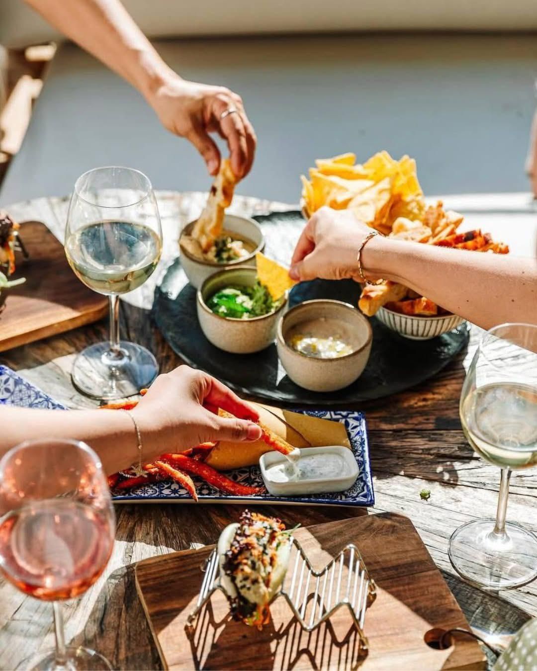 Un gruppo di persone è seduto attorno a un tavolo e mangia del cibo.