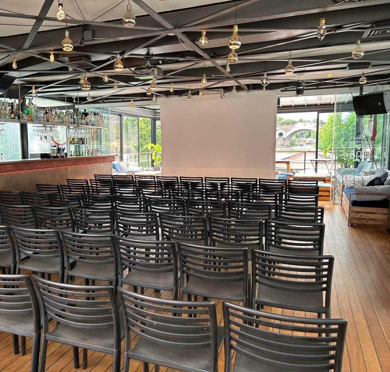 Due uomini sono seduti a un tavolo con i loro computer portatili in una stanza con un fiume sullo sfondo.