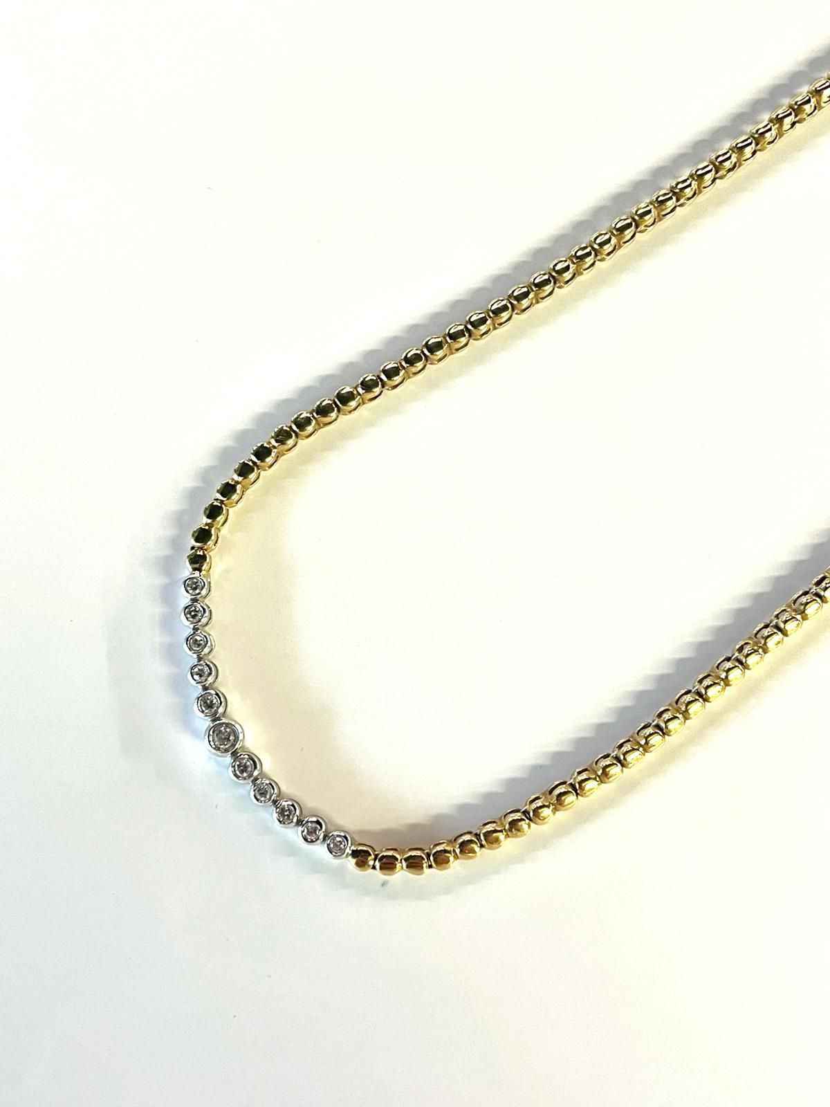 Collana con catena in oro e argento su sfondo bianco.