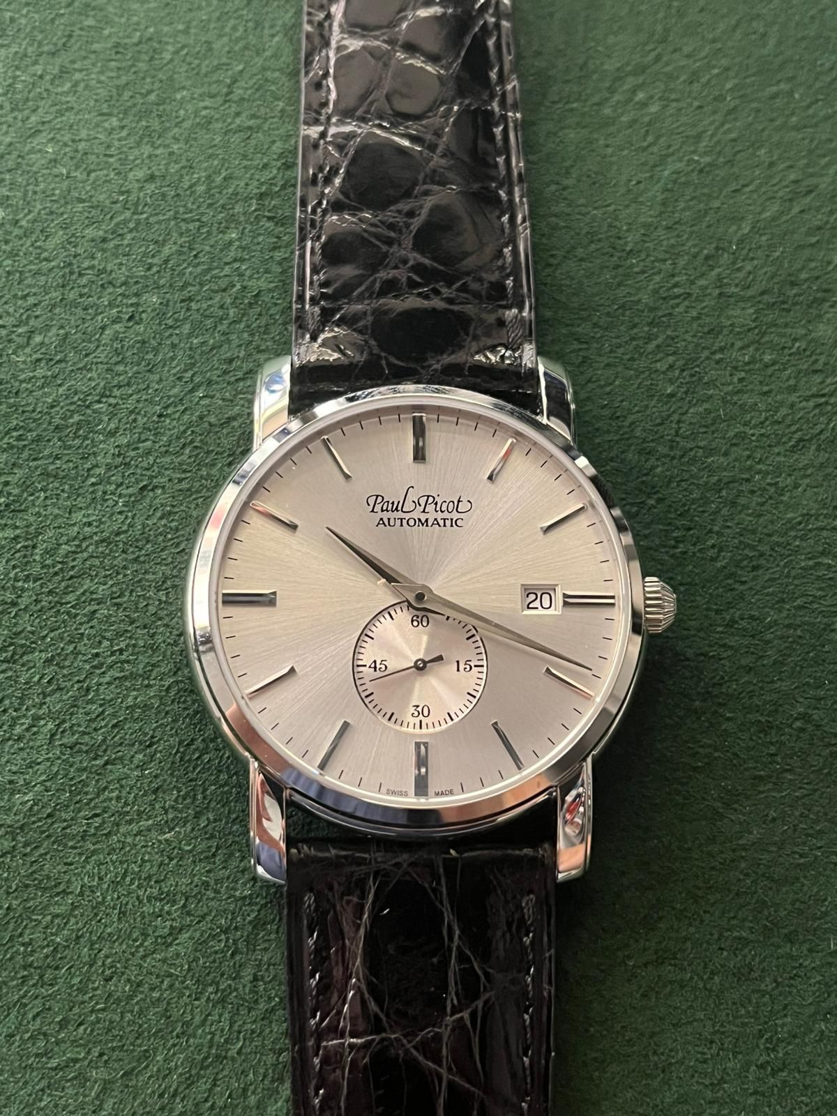 Orologio da polso Paul Rich con quadrante argentato e cinturino in pelle nera su superficie verde.