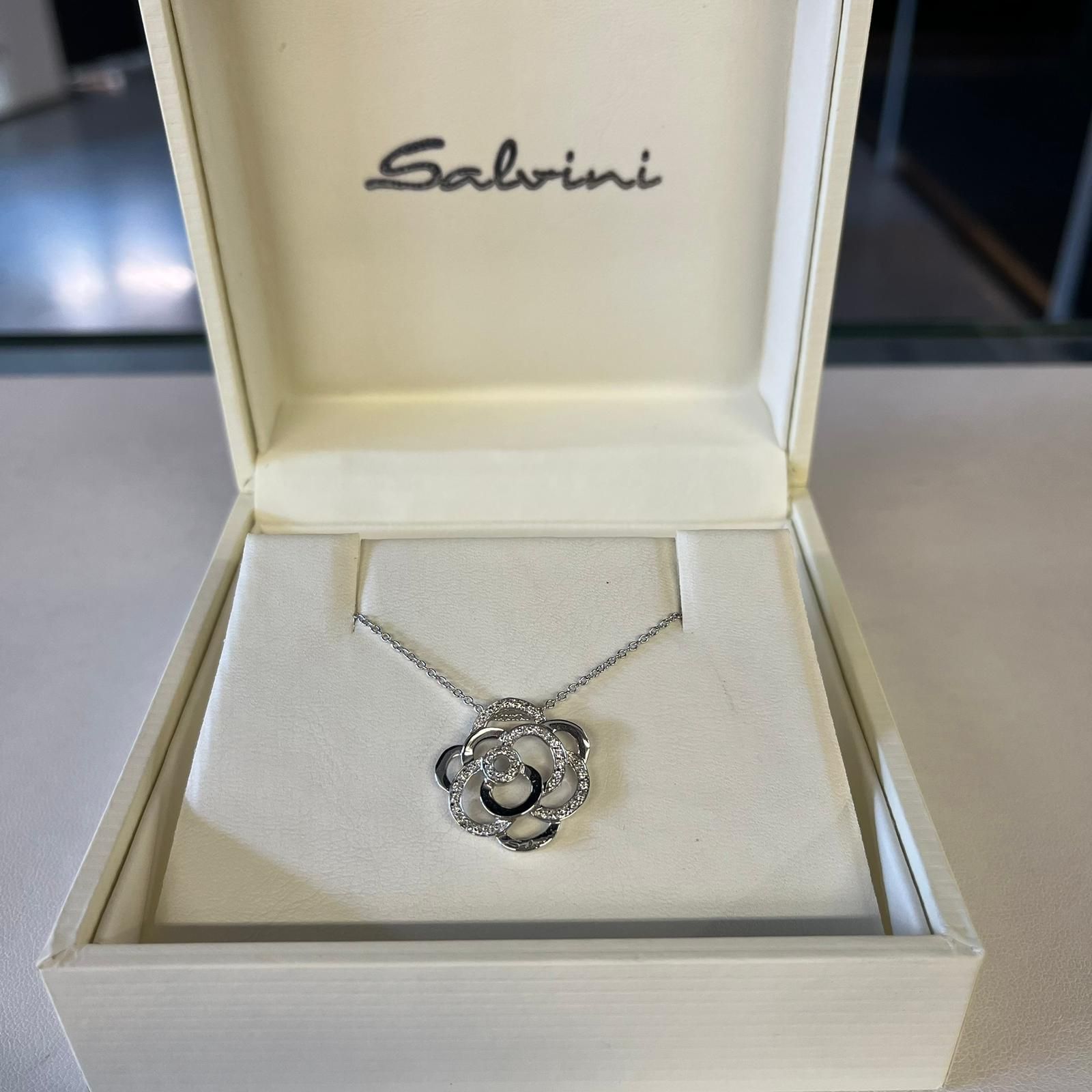 Collana di Salvini in scatola bianca; catena in argento con pendente a forma di fiore con pietre preziose.