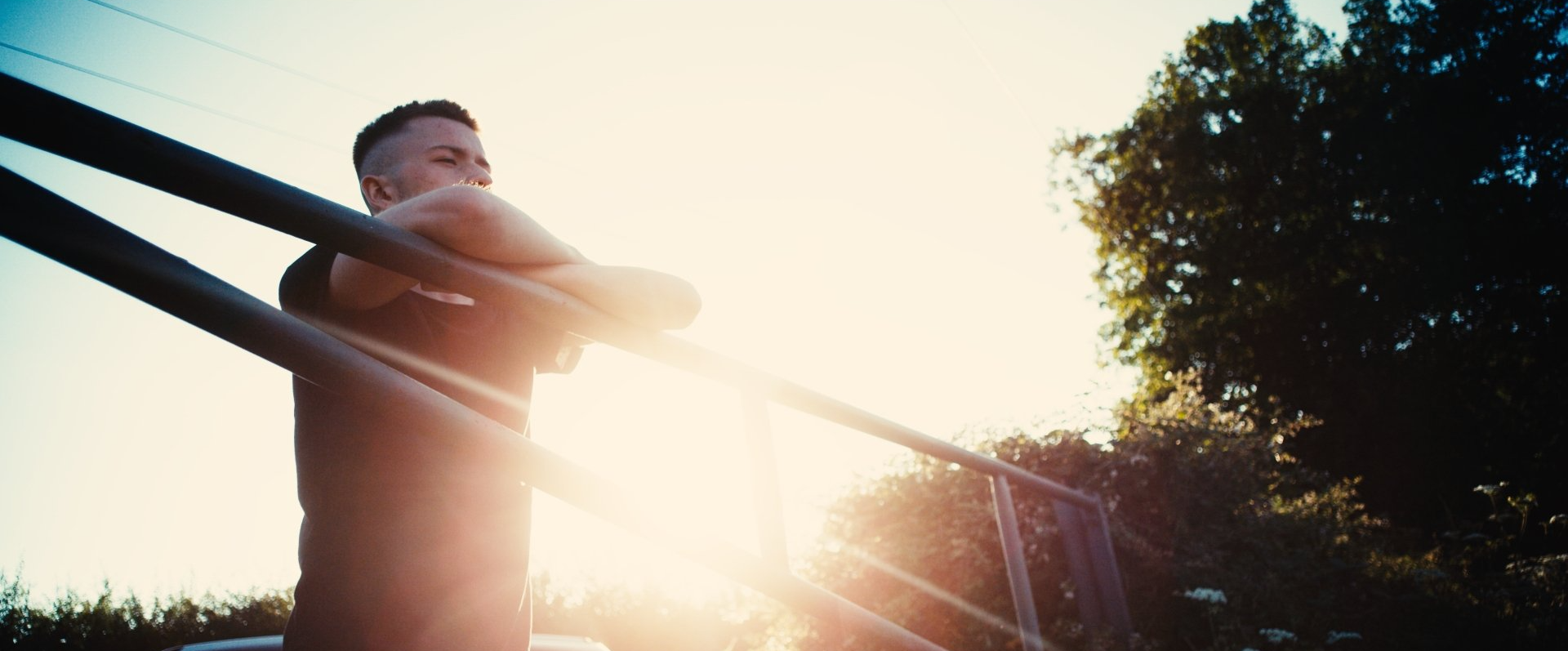 a man is standing on a bridge with the sunset in the background