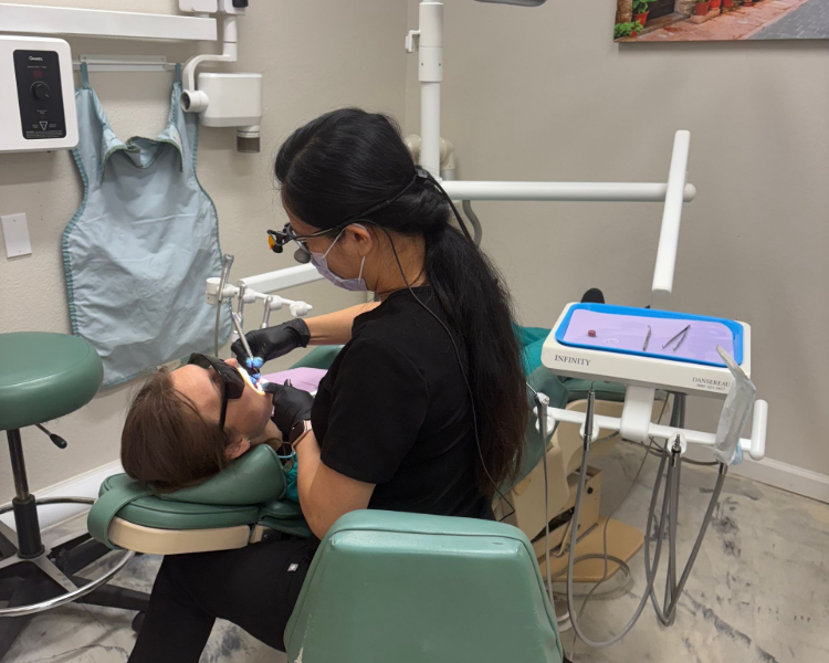 Dentist examining a patient's mouth with a light in a dental office.