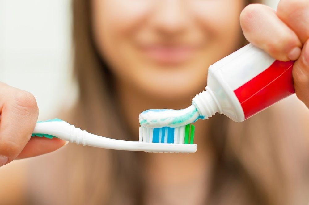 Person squeezing toothpaste onto a toothbrush.