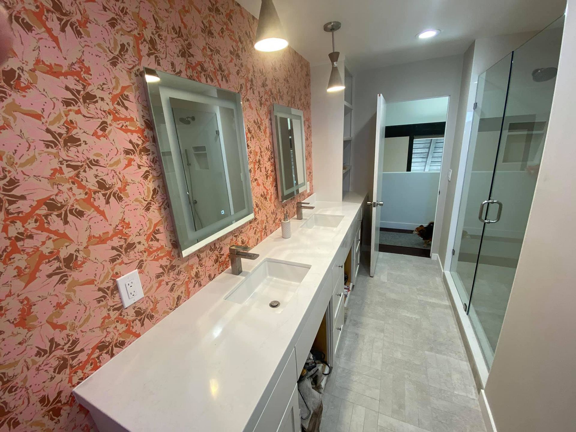 A bathroom with two sinks , two mirrors and a walk in shower.